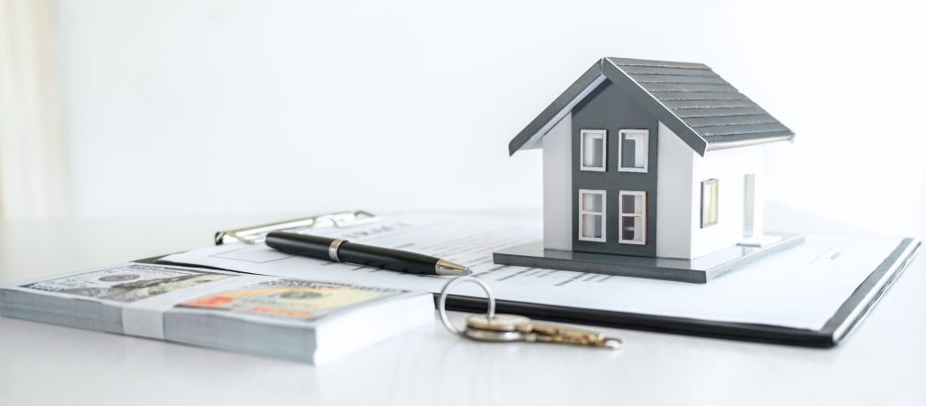 House model and Money, house key lying on real estate contract, home loan and investment concept